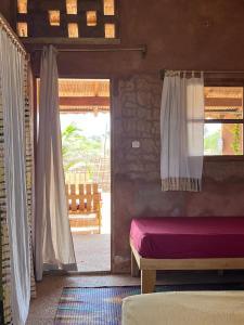 a bedroom with a bed and a door with a window at Mbin Maak du Saloum in Mar Lodj