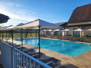 a swimming pool with chairs and umbrellas at L'Oustal de Vézac in Vézac