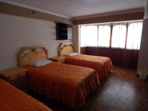 a hotel room with two beds and two windows at Casa de Huespedes Isabella in Sucre