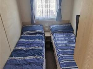 two bunk beds in a small room with a window at Abi tebay oakfields towyn in Kinmel Bay