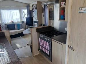 a kitchen with a stove and a living room at Abi tebay oakfields towyn in Kinmel Bay