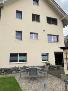 a house with two chairs and a table in front of it at FeWo-Studio Linde in Amsoldingen