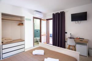 a small room with a bedroom with a desk at Zenia Rooms in San Teodoro