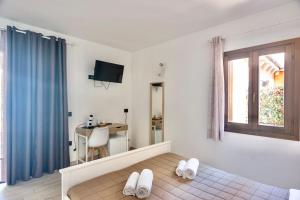 a bedroom with a bed and a desk and a window at Zenia Rooms in San Teodoro