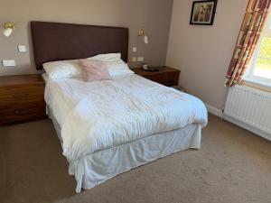 a bedroom with a bed with white sheets and pink pillows at The Moorings in Edmondsley