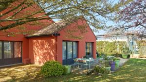 a red house with a table and chairs in the yard at Campanile NATURE Les Ulis in Les Ulis