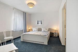 a white bedroom with a bed and a chair at Ferienhäuser Ella Walter - Efeuhaus in Nordstrand
