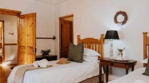 a bedroom with a bed and a table with a mirror at Cypress Cottage - The Old House at River Bend in Graaff-Reinet