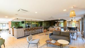 a living room with a couch and a bar at Campanile NATURE - Epône in Épône