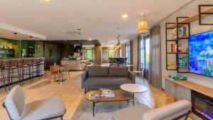a living room with a couch and chairs and a bar at Campanile NATURE - Epône in Épône