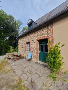 a brick building with a green door and a chair at La Belangerie in Saint-Loup