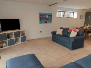a living room with a blue couch and a tv at Harvest Cottage 2 in Berwick-Upon-Tweed