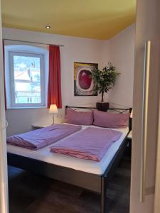 a bedroom with a bed with purple sheets and a window at Ferienwohnung Lienz Egger in Lienz