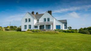 a white house on top of a grass field at Moranedd in Llanfaethlu