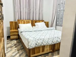 a bedroom with a wooden bed with white pillows at Jk Suites Karatu in Karatu