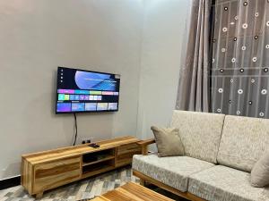 a living room with a couch and a flat screen tv at Jk Suites Karatu in Karatu