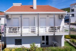 a white house with a balcony and a red roof at Apartmani IVA in Neum
