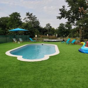 a swimming pool in a yard with chairs and an umbrella at Tipi Big Foot in Vivy