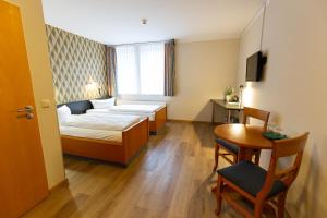 a small room with a bed and a table at Hotel DH VEC in Vechta