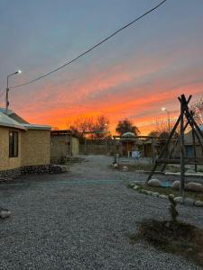 a sunset over a yard with a house and a fence at Altyn Oimok Yurt Camp in Tong