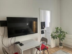 a living room with a white table and a flat screen tv at Petit cocon à 10 min de Paris in Cachan