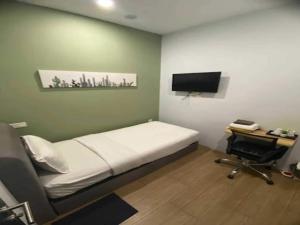 a room with a bed and a desk and a television at Hotel O Green Home Hotel in Sepang
