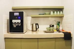 a kitchen counter with a microwave and a sink at Hotel O Green Home Hotel in Sepang