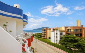 a balcony with a view of the ocean and buildings at Ingleses Holiday Studios in Florianópolis