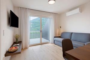 a living room with a blue couch and a large window at Gisshübelhof Apartments in Lana