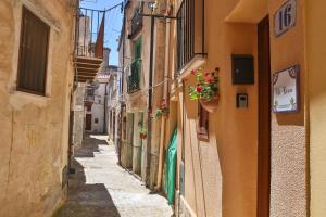 an alley with buildings and flowers in a town at Casa Vacanza Nì Rosa in Cefalù