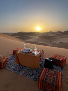 a table in the desert with the sunset in the background at La Source Desert Camp in Adrouine