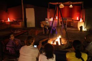 a group of people sitting in a room with a man playing guitar at La Source Desert Camp in Adrouine