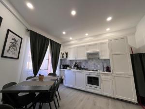 a kitchen with white cabinets and a table and a dining room at Brothers house in Genzano di Roma +25 photos