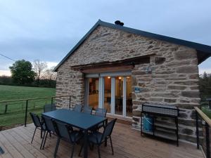 a stone cottage with a table and chairs on a deck at La Grange de Céor in Cassagnes-Bégonhès