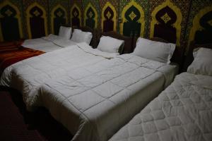 two beds in a room with white sheets at La Source Desert Camp in Adrouine +27 photos