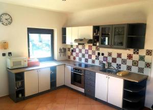 a kitchen with white cabinets and a clock on the wall at Bungalov pod Lípami in Mladějov +3 photos