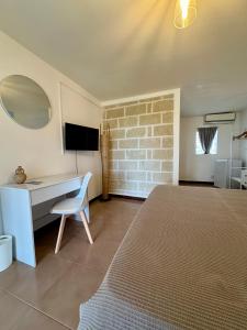 a bedroom with a bed and a desk and a television at Albergo isola mia in Favignana