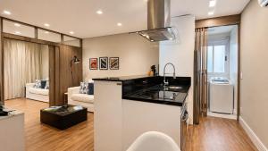 a kitchen with a sink and a living room at Ingleses Holiday Studios in Florianópolis