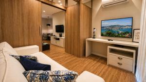 a living room with a white couch and a flat screen tv at Ingleses Holiday Studios in Florianópolis