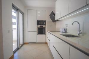 a kitchen with white cabinets and a sink at Rooftop pool & Luxury apartment in Lagos