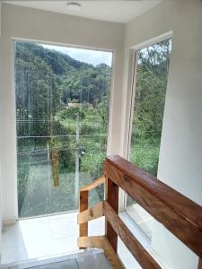 a room with a large window with a view of a river at Pousada Casa Terra de Pinheiros in Santo Antônio do Pinhal