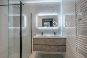 a white bathroom with a sink and a mirror at violette in Pornichet