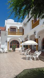a patio with white chairs and an umbrella in front of a building at Hotel Maspalomas in Villa Carlos Paz