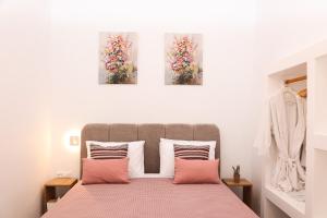 a bedroom with a bed with three paintings on the wall at Town Apartment in Mikonos