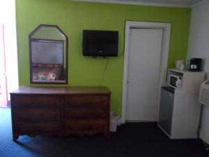 Una habitación con una cómoda y un espejo en una pared verde. en Hillside Motel, en Homer