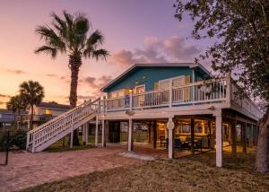 a house with a deck and a palm tree at Haven Steps to Beach Firepit Pet Paradise in Crystal Beach