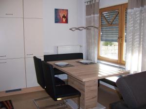 a kitchen with a wooden table with chairs and a window at Ferienwohnung Störkle in Maselheim +5 photos
