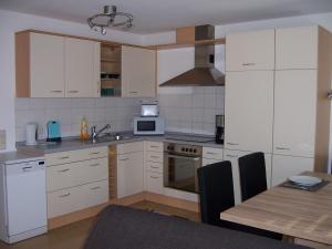 a kitchen with white cabinets and a table and a microwave at Ferienwohnung Störkle in Maselheim