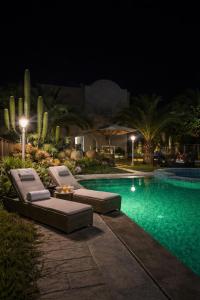 a swimming pool with two lounge chairs next to it at night at Menzel Yahia in Houmt Souk