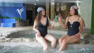two women in bathing suits sitting in a swimming pool at Monte Selva Hotel Spa Termal in Baños